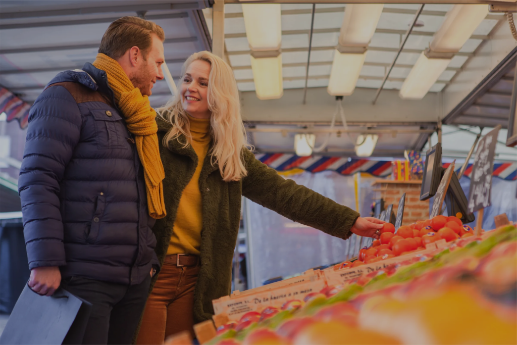 Vrolijke bezoekers bij een marktkraam op de Enschedese markt.